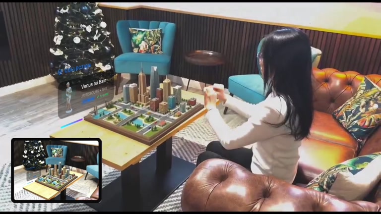 演示视频片段：用户在客厅查看桌面旅行沙盘，照片与旅行内容悬浮在其上方。